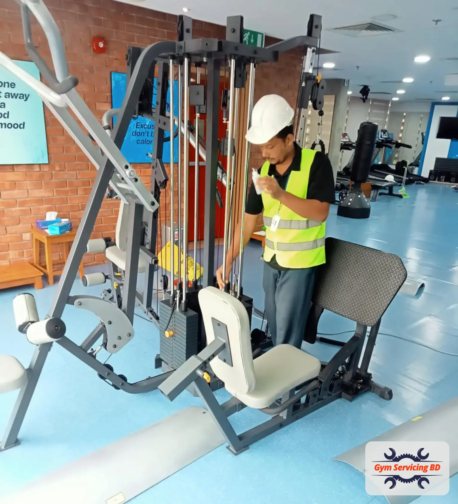 Technician working beside a multi-station gym machine with a clear space around the equipment